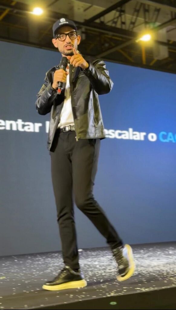 Leonardo Luz no palco, microfone na mão, durante a palestra.